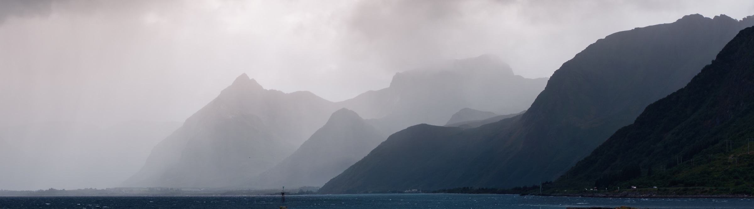 Misty mountain silhouettes along a Norwegian fjord in the Lofoten Islands