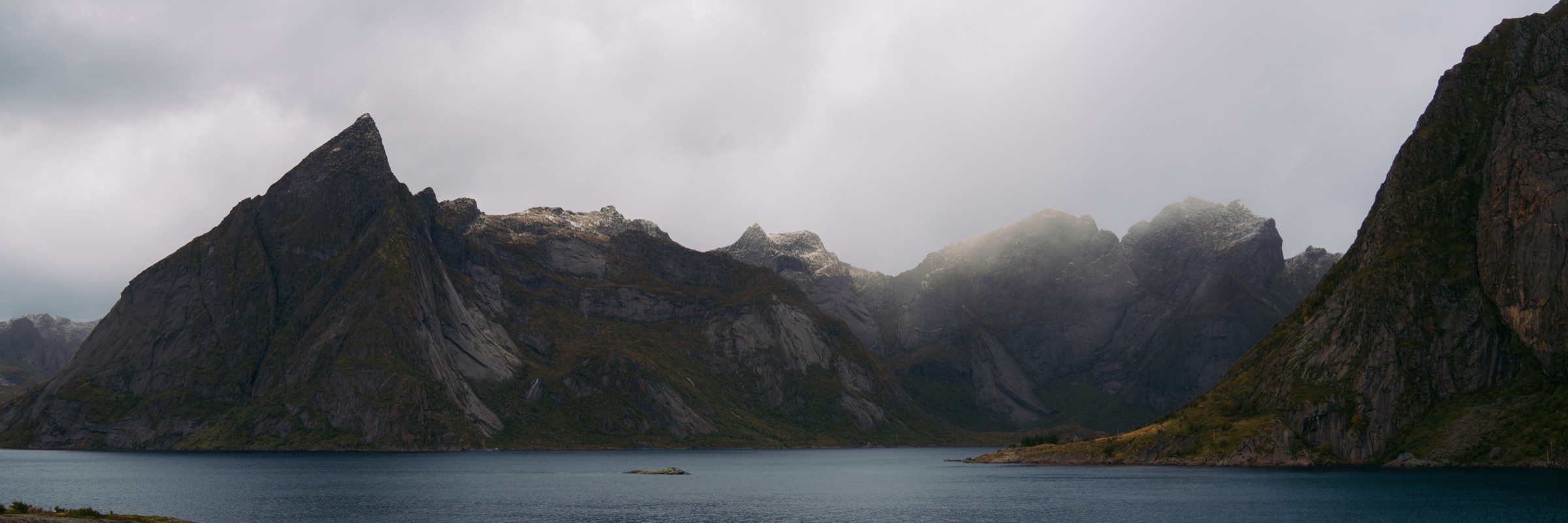 Clouds gathering around sharp mountains beside a fjord in the Lofoten Islands