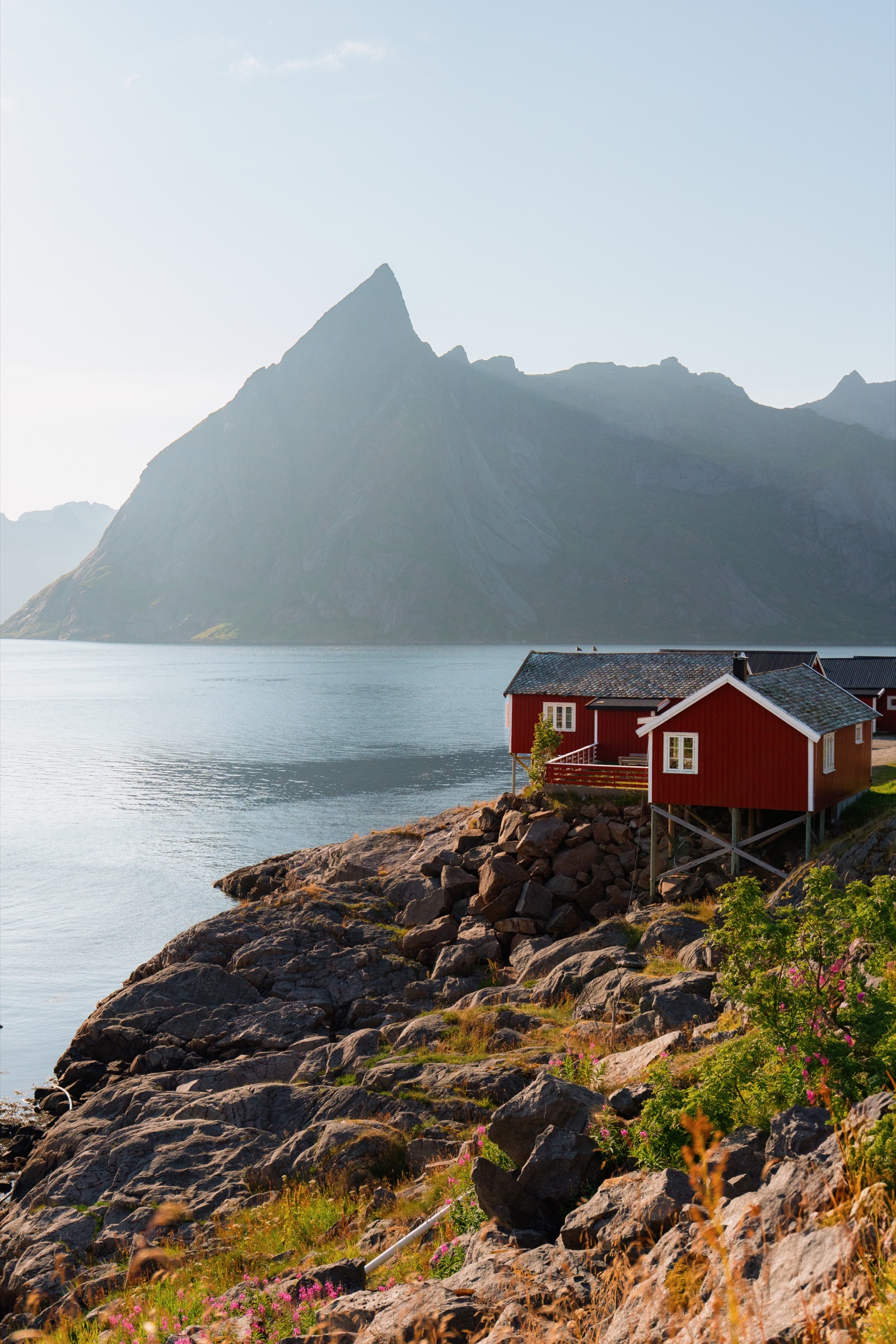 Red cabin below a dramatic mountain ridge in the Lofoten Islands